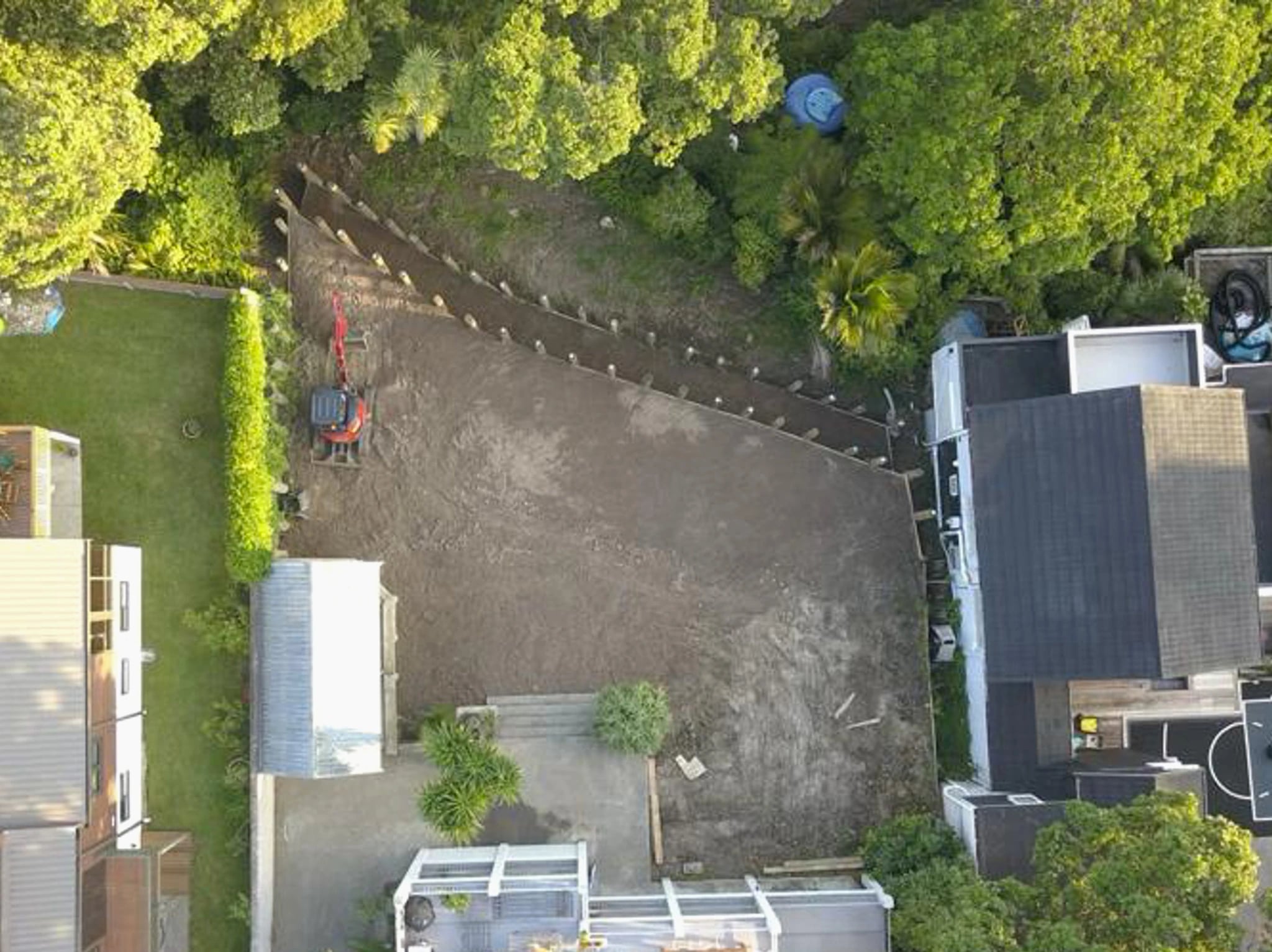 Overhead view of a long retaining line running between two Auckland properties beside a bench of levelled ground